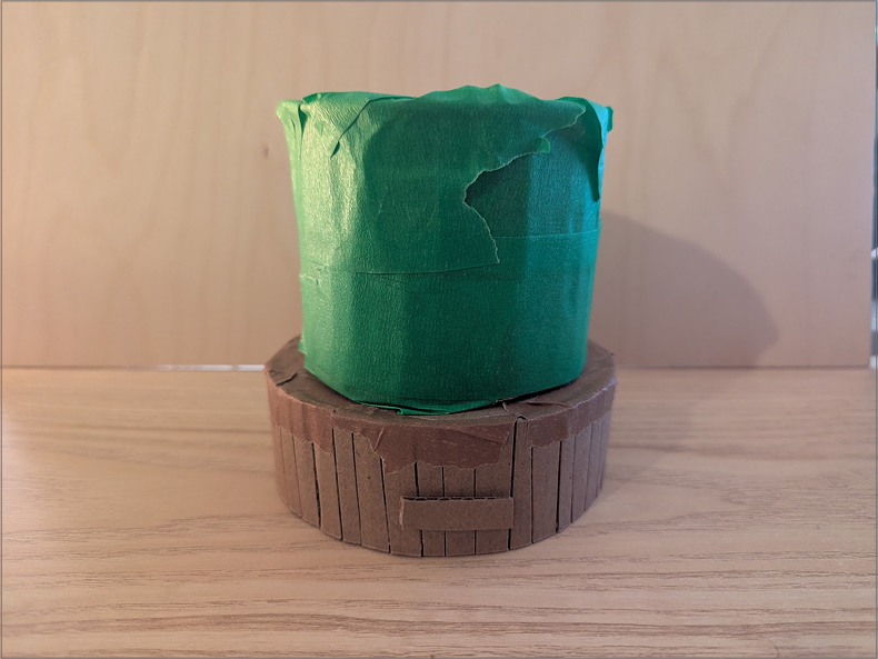 Photo of a lamp prototype. This prototype focuses on being more grounded. The tab on the front would be where a sensor would go. the idea was that this design is larger and would work better with a rounded light. The size of the base would make it so the diffusor could be replaced with another if so desired.